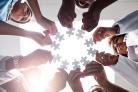 Low angle shot of a group of doctors forming a huddle while each holds a puzzle piece inside of a hospital